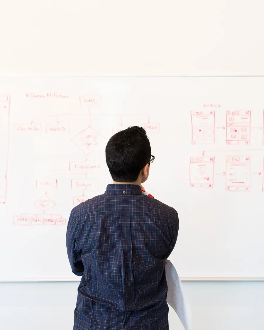 Un tableau couvert de schémas et de notes, une personne devant, de dos